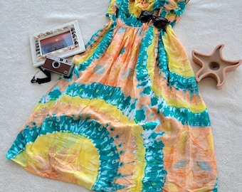 May include: A strapless, tie-dye dress with a yellow, orange, and teal color scheme. The dress has a ruffled top and a flowing skirt.