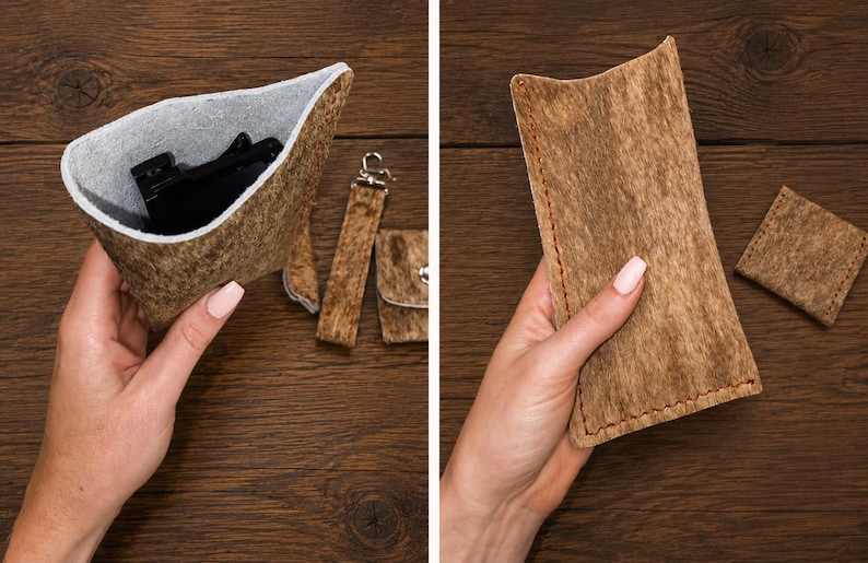 Op de afbeelding: Een bruin, getextureerd etui met een lichtgrijze binnenkant, een bijpassende riem met metalen clip en een klein vierkant tasje. Het etui is open afgebeeld met zwarte inhoud en gesloten met zichtbare stiksels langs de zijkanten.