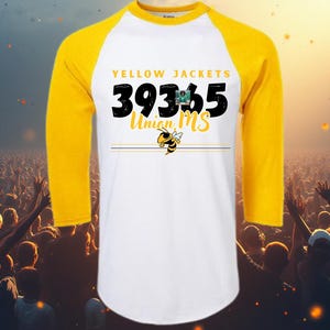 May include: A white and yellow raglan baseball shirt with the text "YELLOW JACKETS 39365 Union MS" in black and yellow. The shirt features a cartoon bee graphic and is likely team apparel.