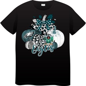 Peut inclure: T-shirt noir avec un motif de citrouille. Le motif comprend un nœud sarcelle et un imprimé léopard, le texte "Eagles" en script sarcelle, une citrouille sarcelle et blanche et une photo d'une personne portant un sweat-shirt vert.