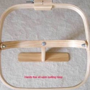 May include: A wooden hands-free quilting hoop with a square frame and a stand. The hoop is designed to hold fabric taut for quilting.