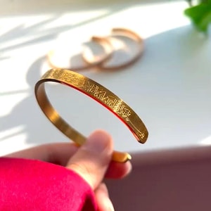 Puede incluir: Un brazalete de oro con una inscripción en escritura árabe.