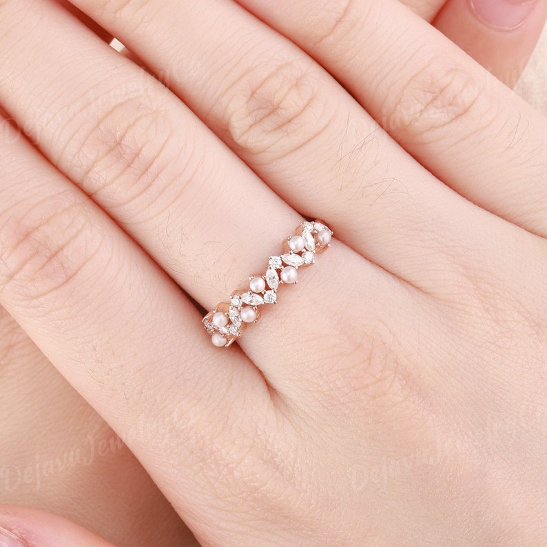 This vintage-inspired pearl wedding ring is a unique and elegant choice for a timeless bride. Crafted in soft rose gold, the band features lustrous pearls nestled between sparkling marquise-shaped moissanite stones.