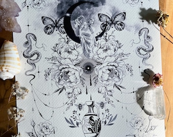 May include: Black and white art print featuring a central design of a statue within a crescent moon, surrounded by flowers, butterflies, and snakes. The print includes an ornate border and the text "THE WILD ..." at the bottom. The overall theme is mystical.