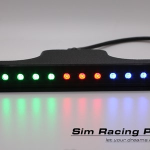 Könnte beinhalten: Ein schwarzes elektronisches Gerät mit einer Reihe mehrfarbiger LED-Leuchten. Die Lichter sind in einer Reihe angeordnet und wechseln von Grün über Rot zu Blau. Das Gerät hat eine rechteckige Basis und einen breiteren oberen Abschnitt, mit einem Kabel.