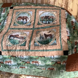 Pode incluir: Uma colcha verde e marrom com um padrão repetido de cavalos em um ambiente de floresta. A colcha é composta por quatro quadrados grandes com uma borda menor ao redor de cada quadrado. Os quadrados apresentam um design circular com uma cena de cavalos no interior. A colcha é acolchoada com um ponto decorativo.