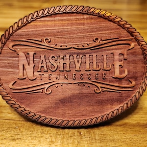 May include: A wooden oval sign with a rope border. The sign is engraved with the words "Nashville Tennessee" in a decorative font.