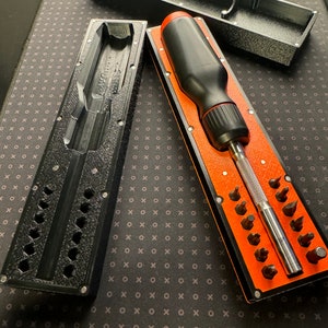 Könnte beinhalten: Ein schwarzes und oranges Schraubendreher-Set mit verschiedenen Bits. Das Set enthält einen Schraubendrehergriff und eine Box mit einem Fach für jedes Bit.