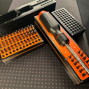 May include: A black and orange screwdriver set with a variety of bits and a screwdriver handle. The set is organised in a black and orange storage case.