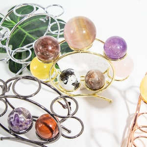 Peut inclure: Deux supports métalliques avec des volutes décoratives tiennent diverses sphères de pierres précieuses polies. Les sphères sont dans des tons de rose, violet, marron, jaune et blanc.