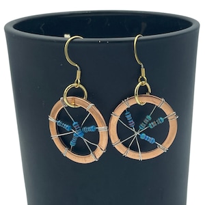 May include: A pair of copper and gold earrings with a circular design. The earrings are decorated with small blue and green resistors.