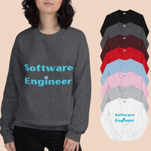 Peut inclure: Un sweat-shirt gris foncé avec l'inscription "Software Engineer" en bleu clair. Le design comprend un petit graphisme coloré. D'autres sweat-shirts noirs, gris, bordeaux, rouges, bleu clair, roses et blancs sont également présentés.