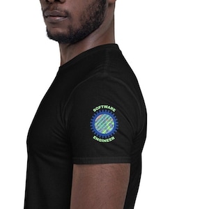 Op de afbeelding: Een zwart T-shirt met een blauw en groen tandwielontwerp op de linkermouw. Het tandwiel heeft de woorden "SOFTWARE ENGINEER" eromheen geschreven.