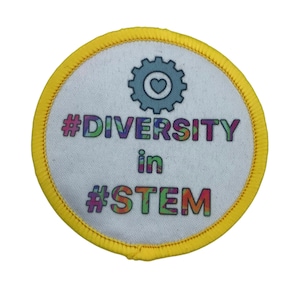 Könnte beinhalten: Ein runder gelber Aufnäher mit weißem Hintergrund und dem Text "#DIVERSITY in #STEM" in Regenbogenfarben. Ein graues Zahnrad mit einem weißen Herzen darin befindet sich über dem Text.
