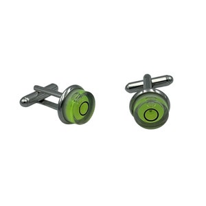 May include: A pair of silver-toned cufflinks with a unique level design. Each cufflink features a clear, circular bubble level with a bright green liquid and a black circular indicator. The cufflinks are designed for a formal or professional look.