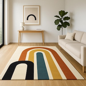 May include: A cream-colored area rug with a retro rainbow design. The rug features bold arches in black, orange, yellow, and teal. The rug is placed on a hardwood floor, with a sofa, table, and artwork in the background.