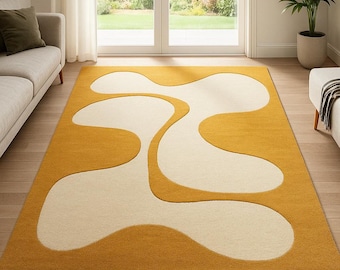 May include: A rectangular area rug featuring a bold, two-tone design with large, organic, cream-colored abstract shapes set against a vibrant mustard yellow background. The rug has a dense, uniform pile texture and clean, curved edges.