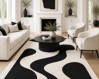 May include: A rectangular area rug featuring a high-contrast design with large, flowing black organic shapes set against a solid cream-colored background. The rug has a thick, textured pile and covers the floor space in front of a round table.