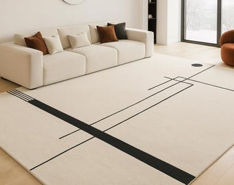 May include: A large rectangular area rug in a light cream color featuring a bold black graphic pattern of intersecting straight lines and a single solid black circle positioned near the upper right corner of the rug's surface.