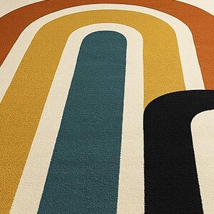 May include: A colorful area rug with a retro design. The rug features a cream-colored background with large, arched stripes in shades of orange, yellow, teal, and black. The design is reminiscent of a rainbow.