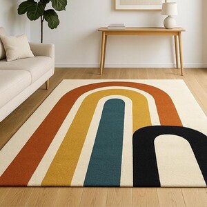 May include: A rectangular area rug with a retro rainbow design. The rug features a cream-colored background with large, curved stripes in shades of orange, yellow, teal, and black. The rug is placed on a hardwood floor.