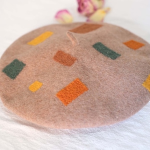 May include: A brown beret with a geometric pattern of orange, yellow, and green squares.