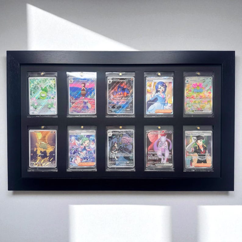 May include: A black framed display case holding ten collectible trading cards. Each card is encased in a clear protective sleeve. The cards feature colorful illustrations of various characters and designs.