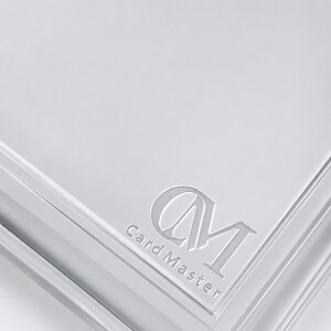 May include: A transparent card holder with the embossed text "Card Master" and the initials "CM". The holder has a glossy finish and is designed to protect and display cards.