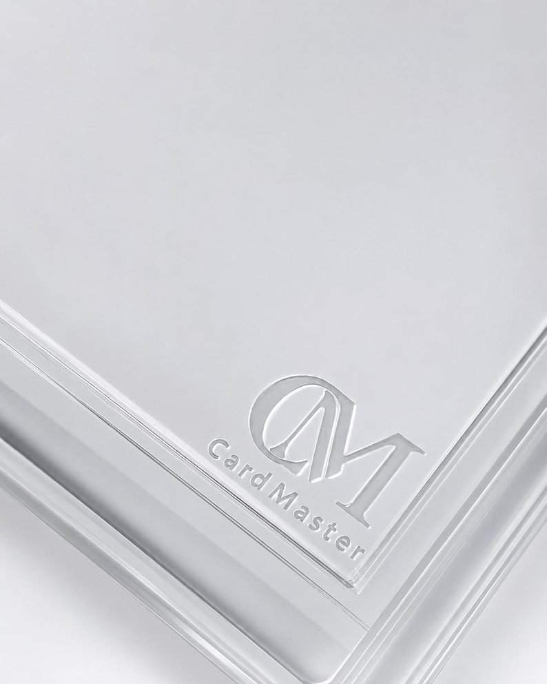 May include: A transparent card holder with the embossed text "Card Master" and the initials "CM". The holder has a glossy finish and is designed to protect and display cards.