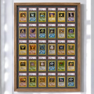 Może przedstawiać: Oprawiona ekspozycja kolekcjonerskich kart Pokémon w stylu vintage. Karty są zamknięte w ochronnych uchwytach i ułożone w rzędach w drewnianej ramie. Karty przedstawiają różne kolorowe ilustracje postaci Pokémon.