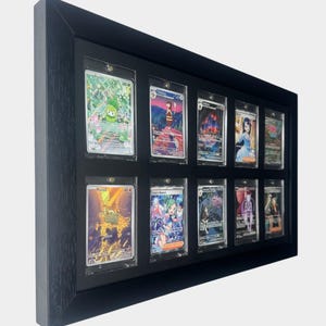 May include: A black framed display case holding twelve trading cards. Each card is encased in a clear protective sleeve. The cards feature colorful illustrations of various characters and scenes.