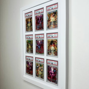 May include: Nine Dragon Ball Super trading cards are displayed in a white frame. The cards are graded and encased in protective plastic. The cards feature various characters from the Dragon Ball Super anime series.