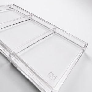 May include: A clear, rectangular acrylic tray with three compartments. The tray has rounded corners and a raised edge. The words "CM Card Master" are printed in a light gray color on the bottom right corner.