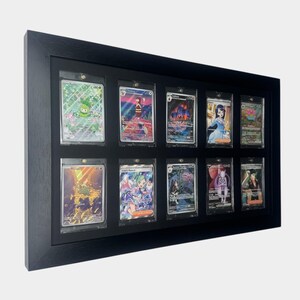 May include: A black framed display case holding twelve collectible trading cards. Each card is encased in a clear protective sleeve. The cards feature colorful illustrations and designs, showcasing a variety of characters and scenes.