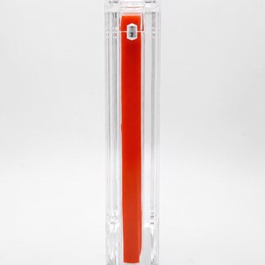 May include: A transparent, rectangular acrylic container with a bright red interior. The container has a vertical design with a silver accent at the top. The overall aesthetic is modern and minimalist.
