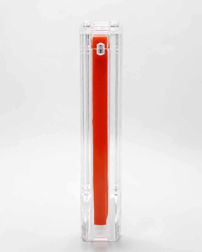 May include: A transparent, rectangular acrylic container with a bright red interior. The container has a vertical design with a silver accent at the top. The overall aesthetic is modern and minimalist.