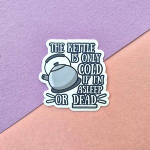 May include: A die-cut sticker featuring a light blue and grey kettle illustration next to the dark blue text that reads: THE KETTLE IS ONLY COLD IF I'M ASLEEP OR DEAD. The design has a white border and a clean, bold, and graphic aesthetic.