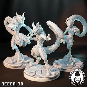 May include: Three light grey 3D-printed figurines of humanoid creatures with insect-like features. Each figure is posed dynamically on a textured base. The figures have segmented bodies, horns, and long tails. The text "BECCA_3D" and "KAIJUMON MINIS" are visible.