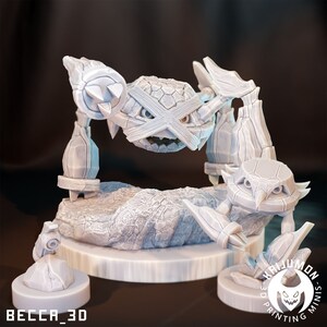 May include: A white 3D printed miniature of a rock-type Pokemon with a menacing expression. The Pokemon has a large, round head with a cross-shaped pattern and four spiky legs. The miniature is set on a rocky base with a smaller rock on the side. The base has the text "KHIJUMON 3D PRINTING MINIS" printed on it.