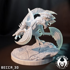 Puede incluir: Un dragón miniatura blanco impreso en 3D con dos cabezas, alas y una cola puntiaguda. El dragón está de pie sobre una base rocosa. La miniatura está impresa por Kaijumon 3D Printing Minis.