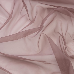 May include: A sheer, lightweight fabric in a dusty mauve or muted rose colour. The material features a fine, semi-transparent mesh texture with soft, flowing folds and drapes that create varying depths of colour across the surface.