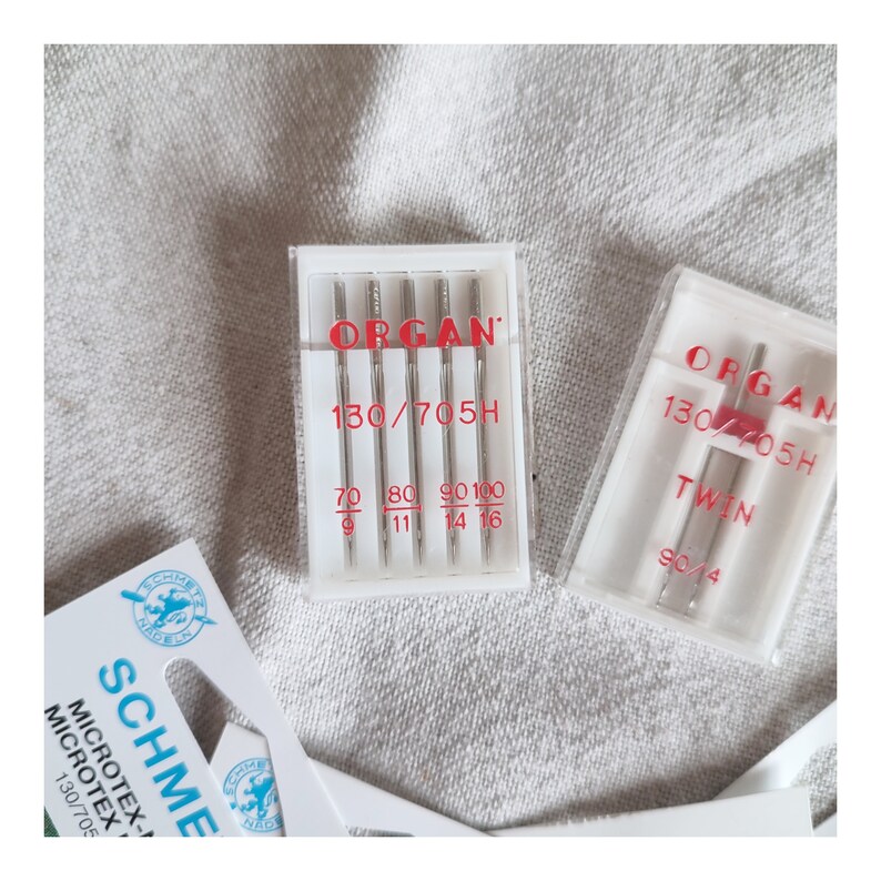 Puede incluir: Dos paquetes de agujas para m&aacute;quina de coser, uno etiquetado como "ORGAN 130/705H" y el otro como "ORGAN 130/705H TWIN 90/4".