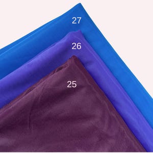 May include: Three layers of semi-sheer fabric stacked diagonally. The top layer is bright blue labelled 27, the middle layer is vibrant purple labelled 26, and the bottom layer is a deep dark plum colour labelled 25. The fabric has a fine mesh texture.