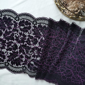 May include: Black lace trim with a purple floral pattern. The lace is delicate and intricate, with a scalloped edge.