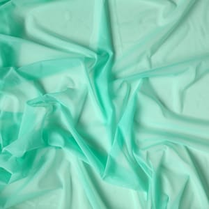 May include: A light green sheer fabric with a soft, flowing texture. The fabric is draped and folded, creating a smooth and elegant look.