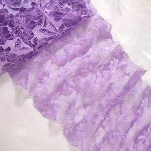 May include: Purple lace trim with a delicate floral pattern. The lace is soft and sheer, with a slightly ruffled edge.