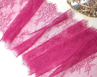 May include: Pink lace trim with a scalloped edge. The lace has a delicate floral pattern.