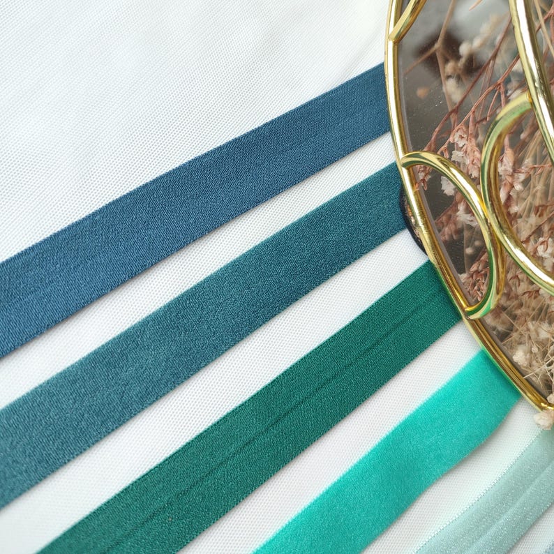 May include: Four different colors of elastic ribbon, from left to right: dark blue, teal, forest green, and turquoise.