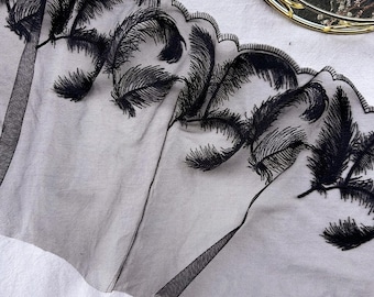 May include: Black embroidered lace trim featuring a repeating feather design. The delicate, scalloped edge adds a decorative touch. This trim is suitable for various sewing and craft projects, adding a touch of elegance.