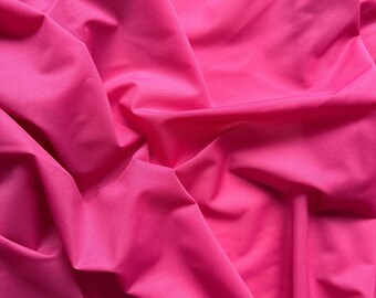 May include: A close-up shot of a vibrant, hot pink fabric. The material is smooth and appears to be a lightweight textile, with soft folds and subtle shadows that add depth. The color is consistent throughout the image.